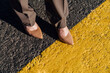 © VISTA by Westend61 - Businesswoman wearing brown stilettos over yellow line marking on road