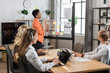 © sofiko14 - African woman in formal wear pointing on glass board with charts and graphs during working conference. Multi ethnic colleagues sitting at desk and listening female partner.