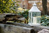 Fototapeta  - Płonący lampion w starym ogrodzie, na wsi, stara drewniana belka, jesienna świeczka, wspomnienie za tych którzy odchodzą