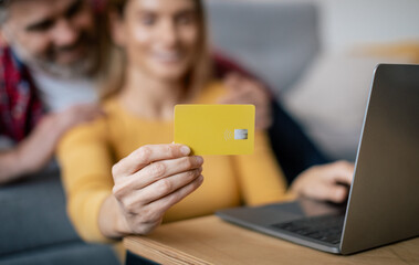 Wall Mural - Finance and banking. Smiling adult european man hugging woman with credit card typing on pc