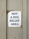 Fototapeta  - NOT A DOG RELIEF AREA sign posted on a building wall