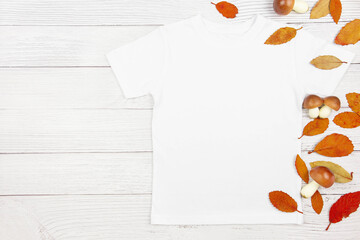 Wall Mural - White womens cotton t-shirt mockup with mushrooms and fallen leaves on white wooden background. Design t shirt template, print presentation mock up. Top view flat lay.