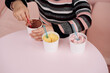 © Disterheft - Child eating ice cream in a cafe. Set of bowls with various colorful Ice Cream with different flavors and fresh ingredients on pink background