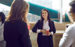 © Studio Romantic - Happy people enjoying a casual chat during a coffee break at work. Group of two cheerful young women and one man standing by the window in a modern office, holding paper cups, talking and smiling