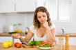 © JackF - Young housewoman eating vegetable salad from plate at home kitchen