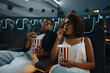 © callisto - A couple with popcorn in an empty cinema watching a movie.