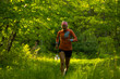 © Cavan Images - woman running in a green field in the forest with orange jacket