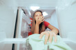 Unhappy Woman Cleaning Stinky Dirty Fridge with a Cloth. Housewife trying to get the rotten spoiled odor out of the freezer
