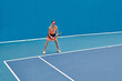 © TrueFrame Collective - Horizontal extreme long shot of young professional tennis player standing on court holding racket getting ready to strike ball