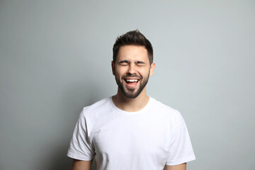 Poster - Young man laughing on light grey background. Funny joke