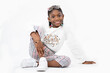 © Kossonoujeanmichel - giovane ragazza sorridente seduta sul pavimento in studio bianco e isolare