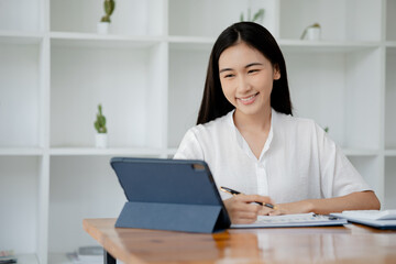 Wall Mural - Asian woman working on laptop, female employee of a marketing company, she is working on a marketing plan for a company to generate income and profit, grow sales. Marketing planning concept.