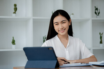 Wall Mural - Asian woman working on laptop, female employee of a marketing company, she is working on a marketing plan for a company to generate income and profit, grow sales. Marketing planning concept.