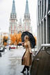 blonde woman in beige coat with black umbrella walking on the street  in the Kyiv  city in autumn