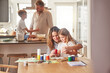 © Alex S/peopleimages.com - Mother painting with child and father cooking with kid in their family home together for growth development and learning. Parents or people teaching children, having fun in kitchen or a holiday house