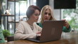 © Marco - Female executive woman explaining job to young female employee in front of laptop at cafe. Female entrepreneur in conversation with staff