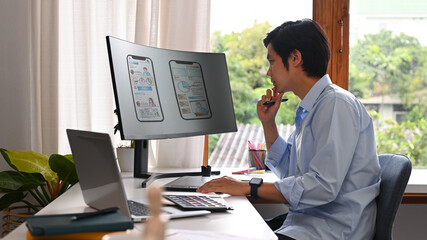 Wall Mural - concentred asian man developer working on mobile application software design project at modern workp
