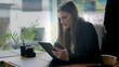 © Marco - Candid young woman sitting at coffee shop reading content online on tablet device. Person paying attention to screen using modern technology