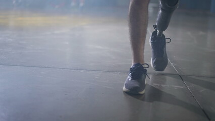 Disabled person walking with his prosthetic leg indoors. Amputee man walks with prosthetic leg