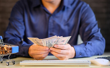 Canvas Print - Businessman hand holding banknote money on desk office and concept of growing business and saving investment.