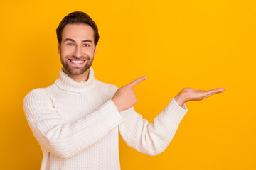 Wall Mural - Photo of positive guy direct finger hand hold empty space wear white pullover isolated yellow color background