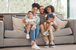 Happy interracial family on sofa portrait of children and parents or mother and father for love, care and support. An immigrant Mexico dad and mom with Asian and african kid together on lounge couch
