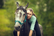 Young girl sits astride a grey horse. Girl rider. Portrait close up