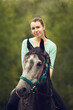 Young girl sits astride a grey horse. Portrait close up. Girl rider