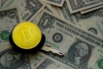 Wall Mural - Closeup shot of a yellow bitcoin, a key and american dollars