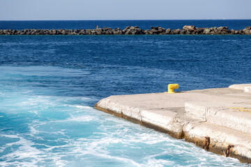 Wall Mural - Greece, Naxos harbor destination Cyclades islands. View of corner of jetty and stone breakwater.