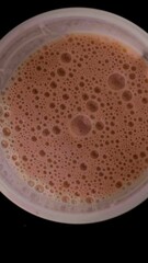 Canvas Print - birdseye shot of a spinning vegan chocolate protein shake against black background