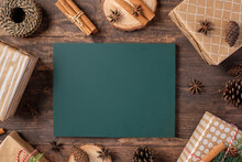 Blackboard With Christmas Gift Box And Present Kraft Wraping Paper On Brown Wooden Table