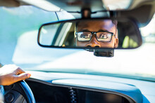 african american man sitting in a car and adjusting rearview mirror looking to back