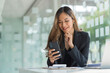© Phushutter - Using mobile, cheerful young asian business woman working at working place.