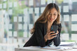 © Phushutter - Using mobile, cheerful young asian business woman working at working place.