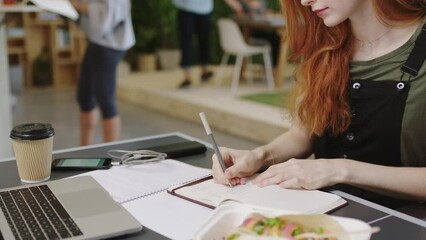 Business woman, writing notes and ux analysis in a busy office as web developer planning digital marketing strategy in a notebook. Female journalist in creative startup agency for software review