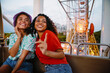 © Drobot Dean - Young multiracial women riding on ferris wheel in attraction park