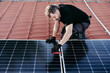 mature Technician man assembling solar panels on house roof for self consumption energy. Renewable energies concept