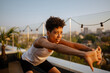 © Drobot Dean - Young black woman in sportswear doing workout on rooftop outdoors