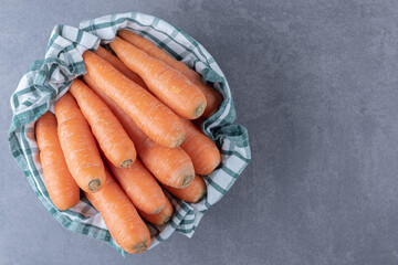 Fresh carrots on towel in the bowl , on the marble background