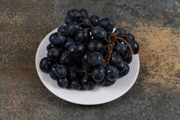 Cluster of black grapes on white plate