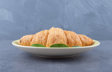 Wall Mural - Fresh French croissant on white plate over grey background