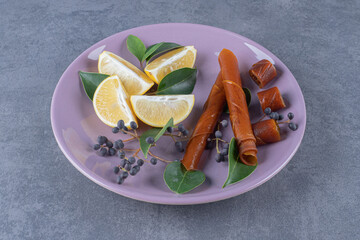 Wall Mural - top view of fresh juicy lemon slices on purple plate