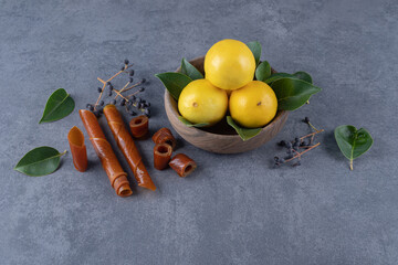 Wall Mural - Bowl of fresh lemons and leaves on grey backgriound