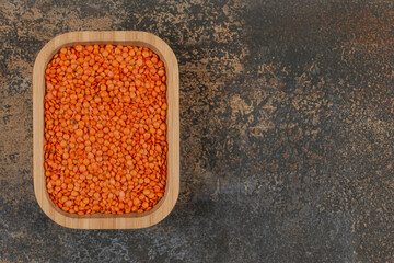 Raw red lentils on wooden plate