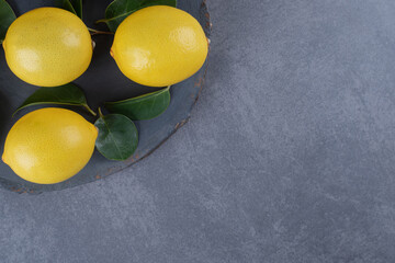 Wall Mural - Three organic lemon on black board over grey background