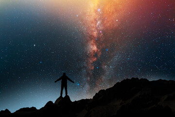 Wall Mural - Hiker silhouette stands on the hill on and looks on the milky way galaxy. Dark starry night