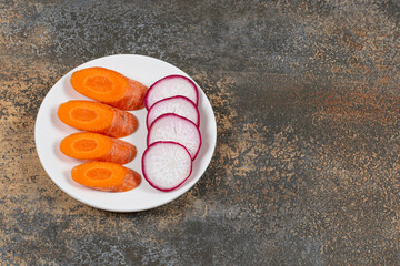 Two healthy vegetables carrot and radish on the plate , on the marble background