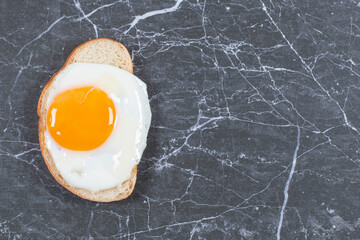 Wall Mural - Flavorful fried eggs on the sliced bread , on the marble background