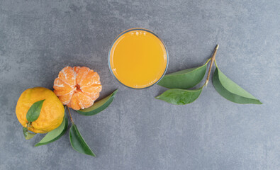 Wall Mural - A glass cup of tangerine juice with leaves